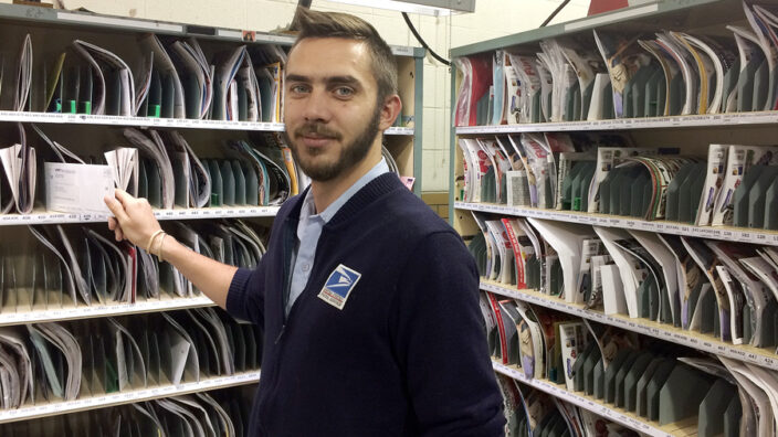 Man sorts mail in uniform