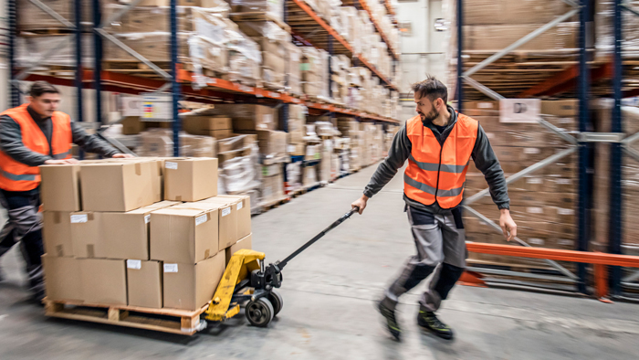 Man in orange vest pulls boxes on cart