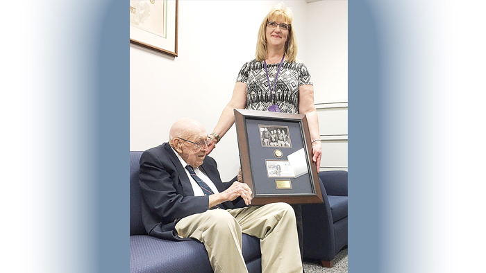 Man sits on couch with woman and plaque