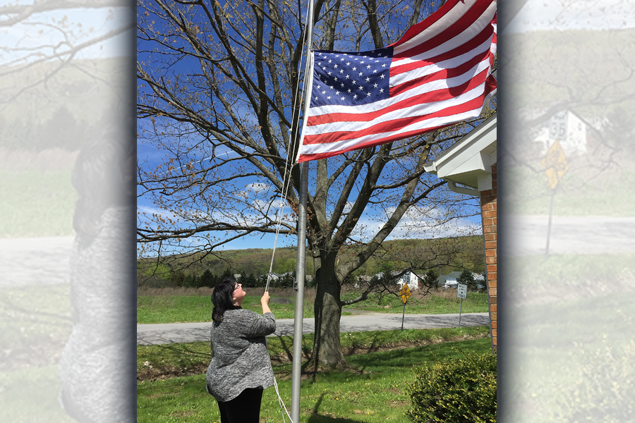 Postmaster Shari Lux raises the U.S. flag