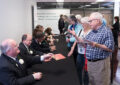 Stamp collectors line up to have their programs autographed by the ceremony’s speakers.