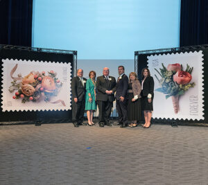 Participants gather on stage after the stamps are unveiled. From left are James Miller, a Missouri Botanical Garden senior vice president; USPS art director Ethel Kessler; Peter Wyse Jackson, president of the botanical garden; Chief Postal Inspector Guy Cottrell; Caggiano; and St. Louis Postmaster Cathy Vaughn.