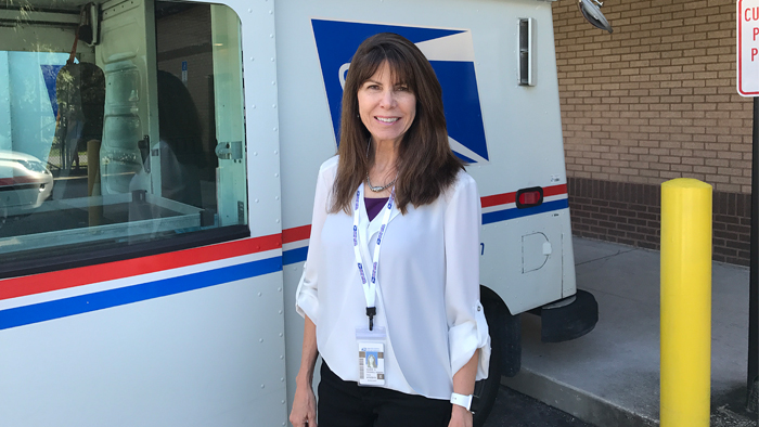 Woman in white shirt in front of postal truck