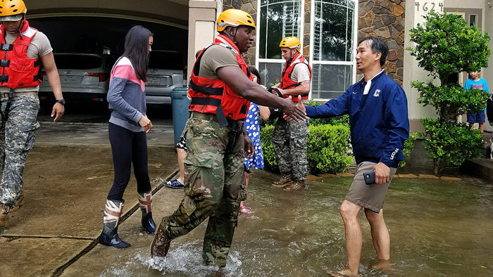 National Guard soldier shakes hands with man outside flooded home