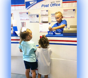 Two girls buy stamps from a boy in blue