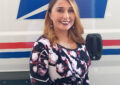 Woman smiles in front of postal truck