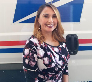 Woman smiles in front of postal truck