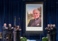 People stand near Father Theodore Hesburgh stamp display