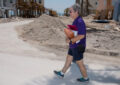 Woman carries mail across sandy surface