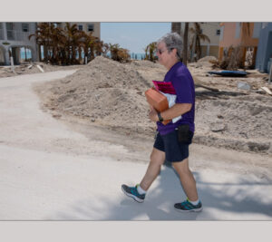 Woman carries mail across sandy surface
