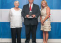 Three people pose with small trophy