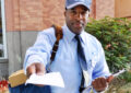 Male letter carrier on sidewalk