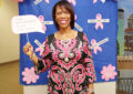 Woman stands in front of breast cancer awareness display