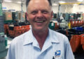 Man in carrier uniform smiles in Post Office