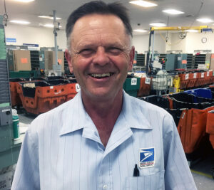 Man in carrier uniform smiles in Post Office