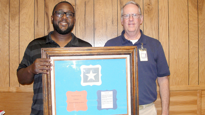 Two employees holding award