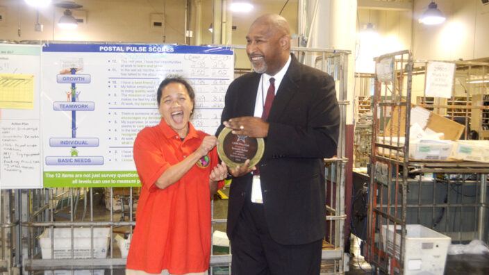 Woman receives trophy from man