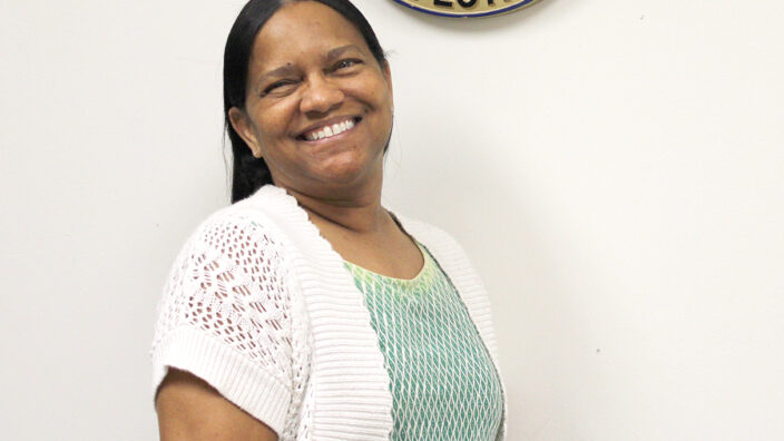 Woman smiles under sign