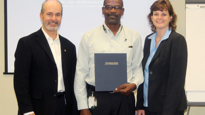 Three USPS employees posing with certificate