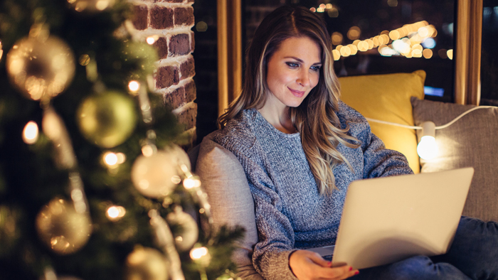 Woman on computer by Christmas tree