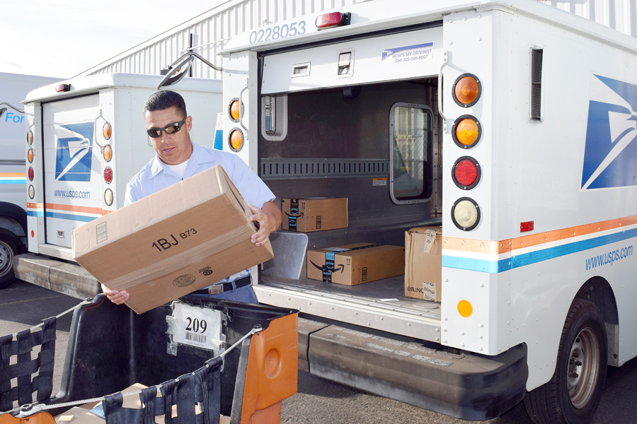 Letter carrier loads postal vehicle