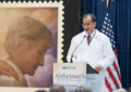 Man in lab coat stands at podium