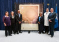 People stand in front of oversized stamp artwork