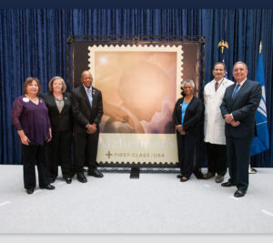 People stand in front of oversized stamp artwork
