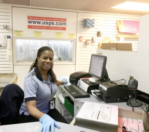 USPS retail worker smiles behind counter