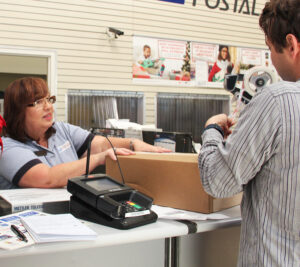 Postal worker serving customer at counter