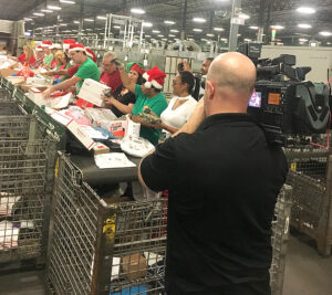 TV cameraman films postal workers on assembly line