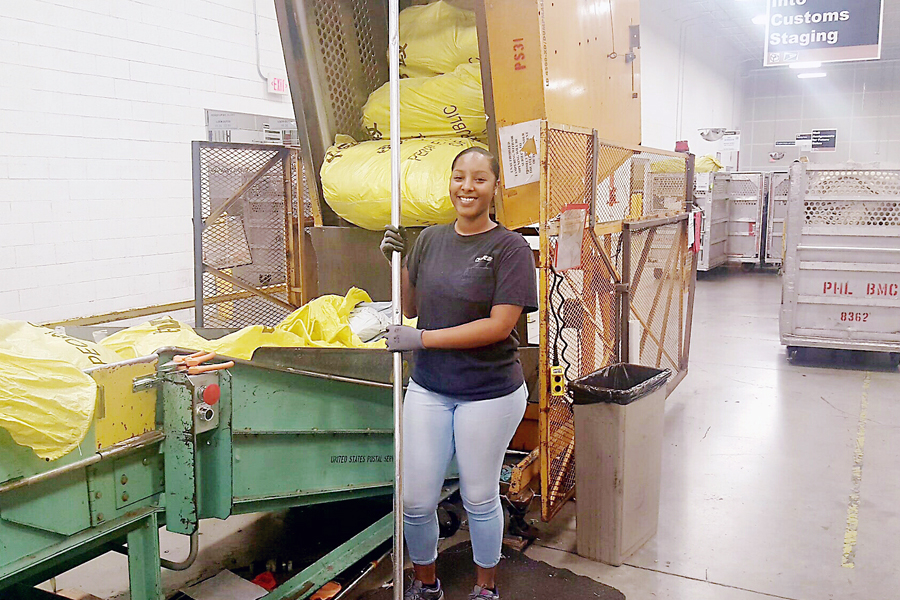 Employee standing in front of mail sorter