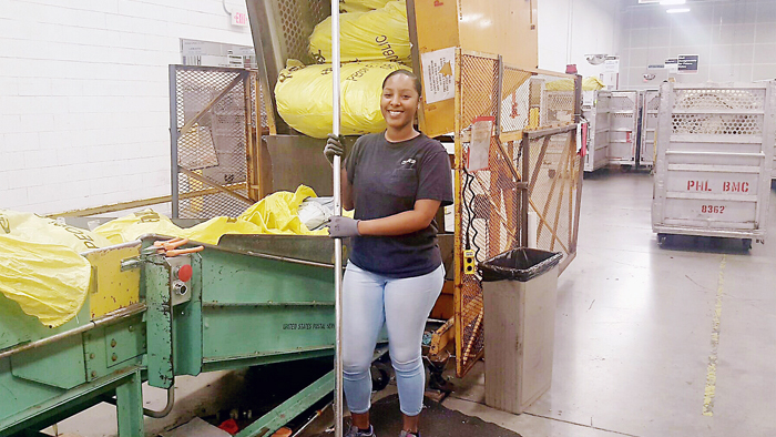 Employee standing in front of mail sorter
