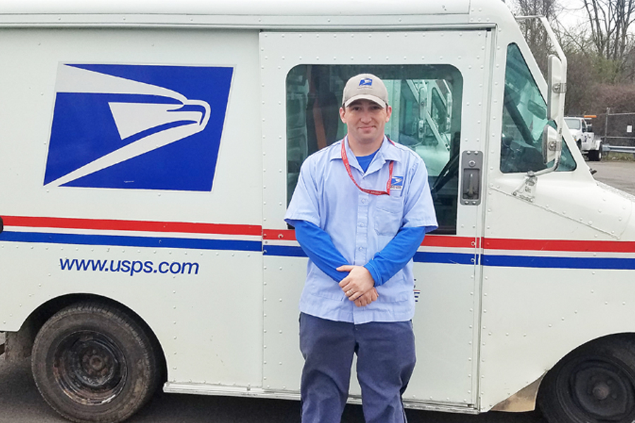 Employee poses beside postal truck