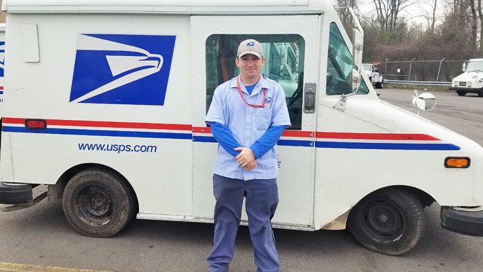 Postal employee poses beside postal truck