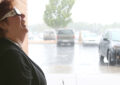 Smiling woman wearing eclipse glasses smiles during downpour