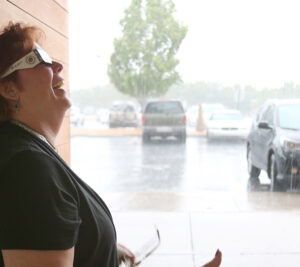 Smiling woman wearing eclipse glasses smiles during downpour