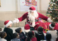 Santa Claus spreads his arms wide as he speaks to children