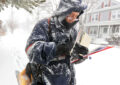 Letter carrier carries mail during heavy snowfall