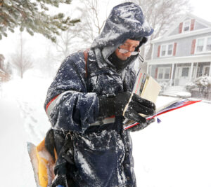 Letter carrier carries mail during heavy snowfall