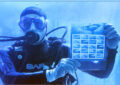 Diver holds stamp sheet in water tank