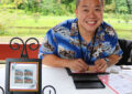 Man sits at table, applying hand stamp to envelope