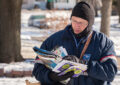 Letter carrier in heavy gear looks at mail