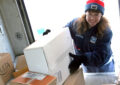 Letter carrier places package inside delivery vehicle