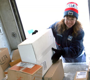 Letter carrier places package inside delivery vehicle