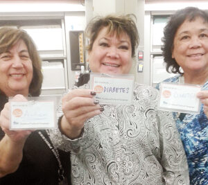 Three women hold tags with charitable causes written on them