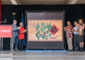 People stand near large display of stamp artwork