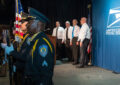 Uniformed police officers holding flags stand near singers on stage