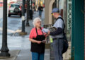 Older woman speaks to letter carrier on downtown sidewalk