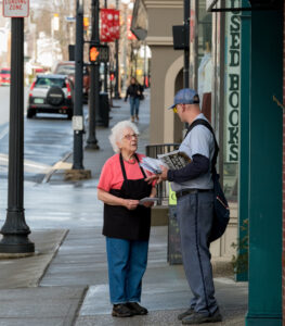 Older woman speaks to letter carrier on downtown sidewalk